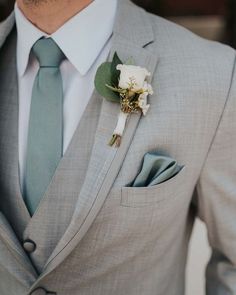 a man wearing a gray suit and tie with a flower in his lapel pocket