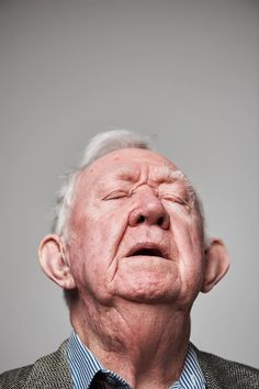 an older man with white hair wearing a suit and tie looking up at the sky