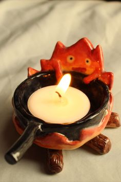 a candle that is sitting in a bowl on top of a wooden stick and some kind of animal figurine