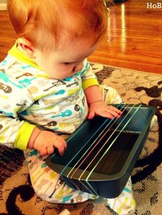 a baby sitting on the floor playing with an open suitcase