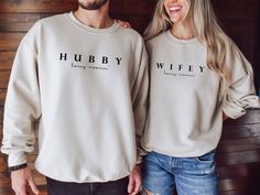 two people standing next to each other wearing sweatshirts that say hubby and wife