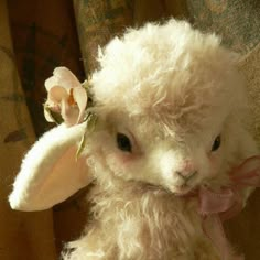 a white stuffed animal with a flower in its hair