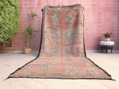 an old rug sitting in front of a brick wall with potted plants on it