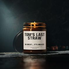 a candle that is sitting on a table in front of a dark background with the words tom's last straw