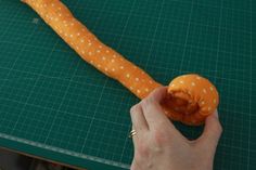 a person holding an orange object on top of a green cutting board next to a knife