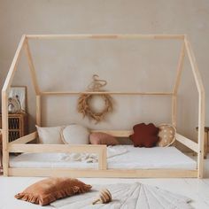 a wooden bed frame with white sheets and pillows on the floor in front of it