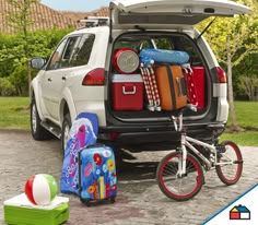 a white car with luggage and suitcases in the back seat is parked next to a child's bike