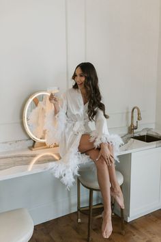 a woman sitting on top of a counter next to a mirror