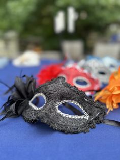 three masks are sitting on a blue table cloth with orange and red flowers in the background