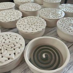 many white bowls with designs on them sitting on a counter top next to each other