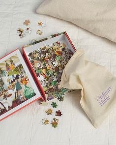 an open puzzle box sitting on top of a bed next to a cloth bag and pillow