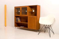 a white chair sitting in front of a wooden bookcase next to a yellow pole