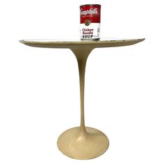 a can of paint sitting on top of an oval table with a gold pedestal base