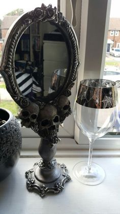 a wine glass sitting next to a mirror on a window sill