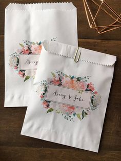 two white paper bags with floral designs on them, one has a name tag attached to it