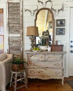 an old dresser with antlers on it and a lamp in front of the mirror