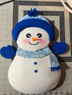 a snowman made out of felt sitting on top of a table next to a ruler