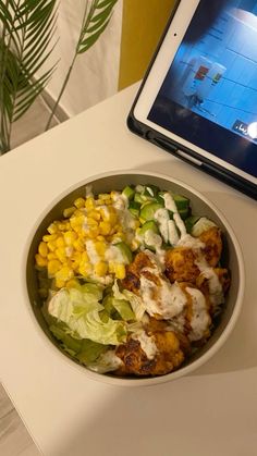 a salad in a bowl next to an ipad