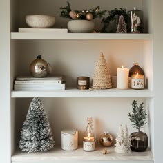 shelves with candles, christmas trees and other decorations on them in a living room or dining room