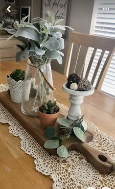 a wooden table topped with potted plants on top of a doily covered table