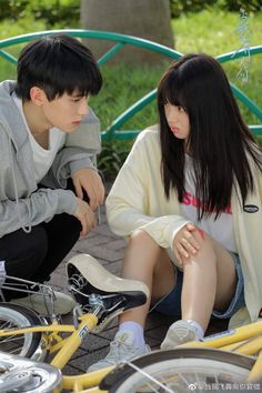 two people sitting on the ground next to bicycles