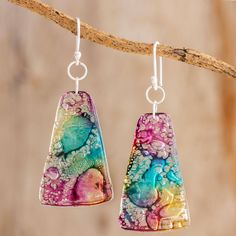 the earrings are colorful and have different designs on them, including one that is hanging from a branch