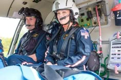 two fire fighters sitting in the back of an ambulance with breathing apparatus attached to their helmets