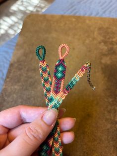 a person is holding an object made out of beaded string and beads with scissors