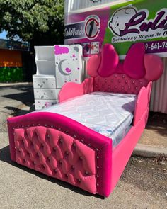 a bed made out of cardboard with pink headboard and foot board on the ground