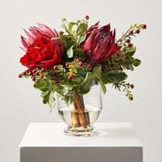 a vase filled with red flowers on top of a white table