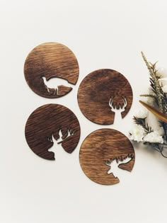 four deer and antelope wooden coasters on a white surface with flowers in the background