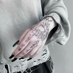 a woman's hand with black and white tattoos on her left arm, holding onto the