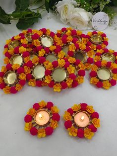 a bunch of candles sitting on top of a table next to some flowers and greenery