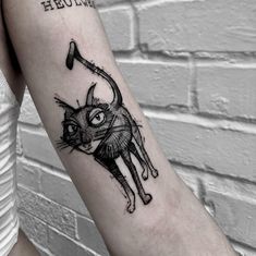 a black and white cat tattoo on the left arm with an arrow in its mouth