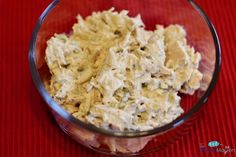 a glass bowl filled with chicken salad on top of a red tableclothed surface