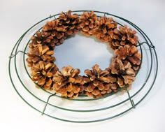 a wreath with pine cones is on a wire rack, ready to be put in the oven