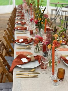 a long table set with place settings and flowers in vases on the top tables