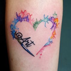 a colorful heart tattoo with scissors and paint splatters on the side of it