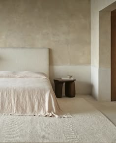 a white bed sitting next to a wooden table on top of a carpeted floor