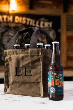 two bottles of beer and a tote bag sitting on a table