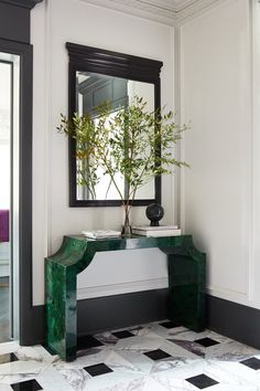 a green console table with a potted plant on it in front of a mirror