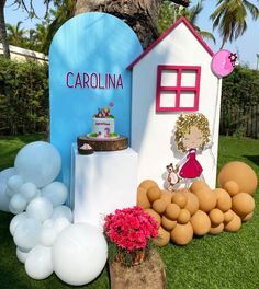 there is a cake and balloons set up on the lawn for a baby's first birthday