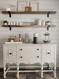 a kitchen with white cabinets and open shelving above the counter top, along with coffee cups on shelves