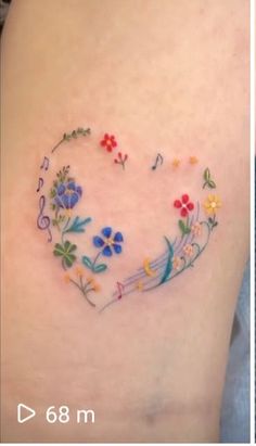 two pictures showing the same tattoo on each side of their thighs, one with flowers and music notes