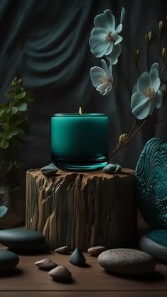 a green candle sitting on top of a wooden table next to rocks and a potted plant