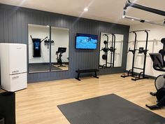 a gym with exercise equipment and mirrors on the wall, in front of a flat screen tv