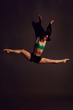 a woman in black shorts and a green bra top is doing a trick with her legs