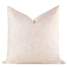 a pink pillow with white flowers on the front and back, sitting on a white surface