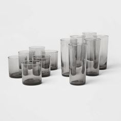 a set of nine glasses sitting next to each other on a white surface with one empty glass in the middle