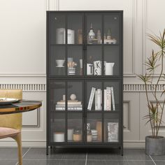 a glass cabinet with books on it next to a table